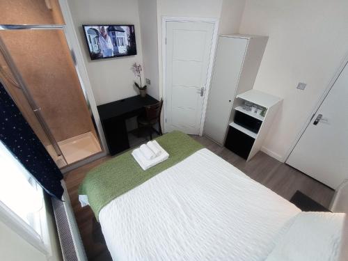 a small room with a bed with a green blanket at The Maple Studio - Self contained one bed studio flat in Oxford