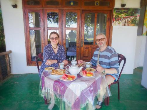 a man and woman sitting at a table with food at Ella Happy View Homestay in Ella