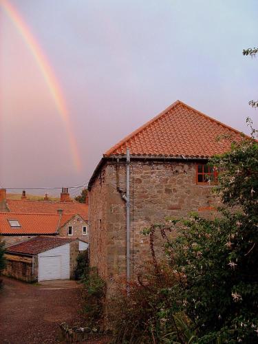 a rainbow in the sky behind a brick building at The Old Mill in Wooler