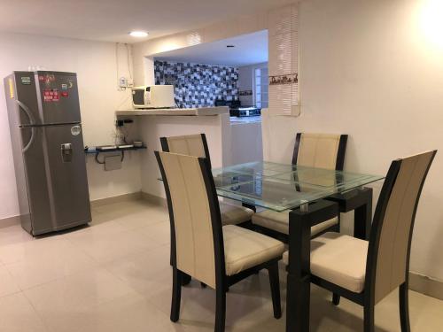 szklany stół i krzesła w kuchni z lodówką w obiekcie Martinica Hostel w mieście Cartagena de Indias