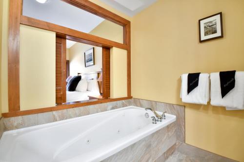 La salle de bains est pourvue d'une baignoire et d'un grand miroir. dans l'établissement Ski in Ski Out at Sundial Lodge Walk out to Pool 2BR C006, à Park City