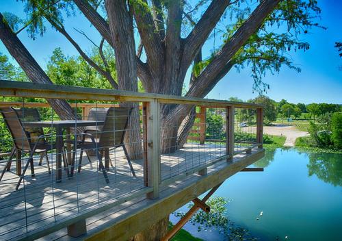 a deck with a table and chairs next to a tree at Treetop River Cabins on the Guadalupe River in Center Point