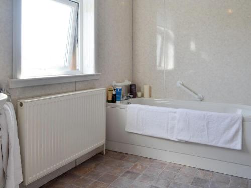 a white bathroom with a tub and a window at Cardoness House in Dumfries