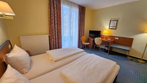 a hotel room with two beds and a desk and a window at Hotel Amadeus Dresden Neustadt in Dresden