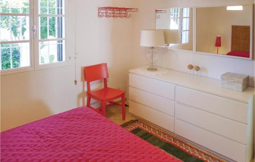 een slaapkamer met een bed en een dressoir met een rode stoel bij Stunning Apartment In Mezquitilla With Kitchen in Mezquitilla