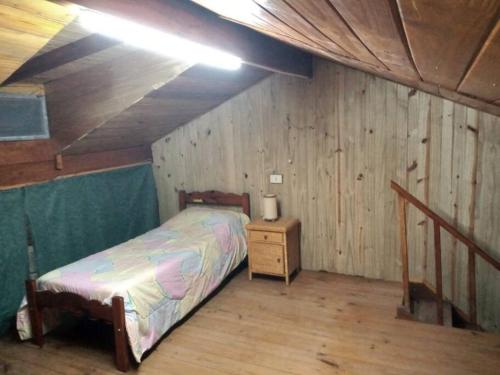1 dormitorio con 1 cama y pared de madera en Amplio depto para 4 personas a 1 cuadra del mar en Balneario Mar Chiquita