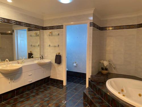 Banksia Beach的住宿－SPECTACULAR WATERFRONT Canal Home, BRIBIE ISLAND，大型浴室设有两个盥洗盆和浴缸。