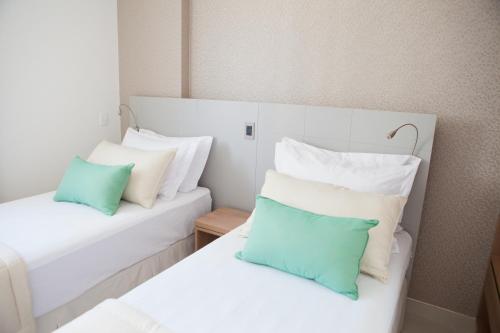 two beds with blue and white pillows in a room at Intercity Brasilia Led Aguas Claras in Brasilia