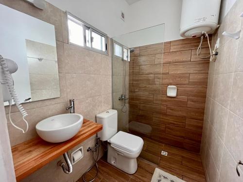 a bathroom with a white toilet and a sink at Hotel Lobato in Paysandú