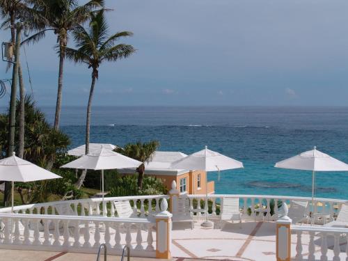 a house with a balcony with umbrellas and the ocean at Coco Reef Bermuda in Mount Pleasant