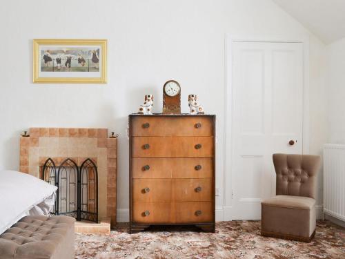 a bedroom with a dresser and a clock and a chair at Moray Cottage in Wick