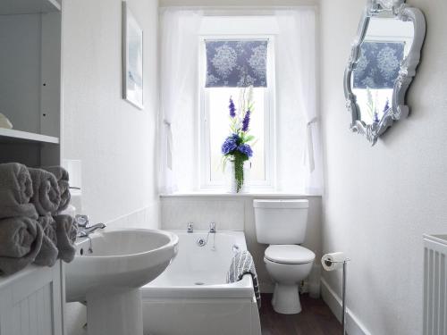 a white bathroom with a sink and a toilet and a window at Moray Cottage in Wick