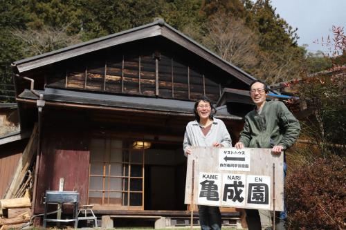 a man and woman holding a sign in front of a house at Kamenarien in Ema