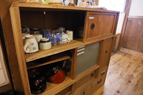 a wooden cabinet filled with cups and jars at Kamenarien in Ema