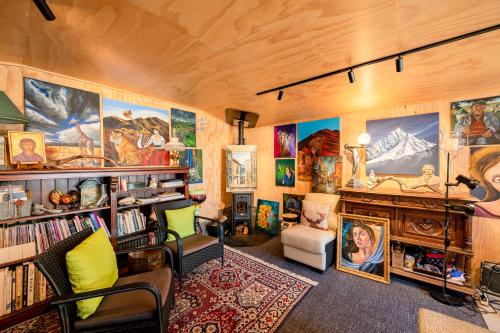 a living room with a lot of paintings on the walls at Criffel Bluffs Cottage in Wanaka