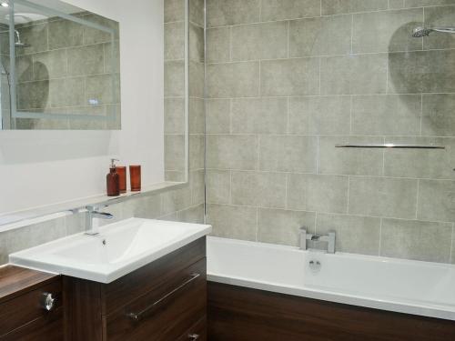 a bathroom with a sink and a bath tub at Stable Cottage in Stewarton