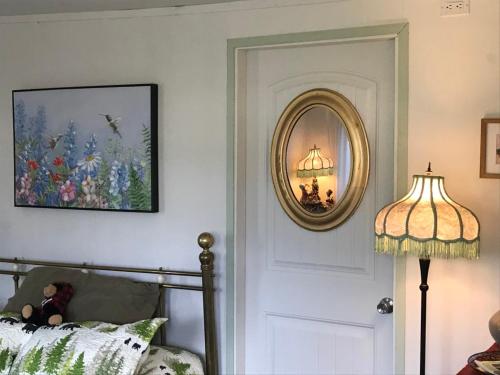 ein Schlafzimmer mit einem Spiegel, einem Bett und einer Lampe in der Unterkunft Meadow Suites in Wells in Barkerville