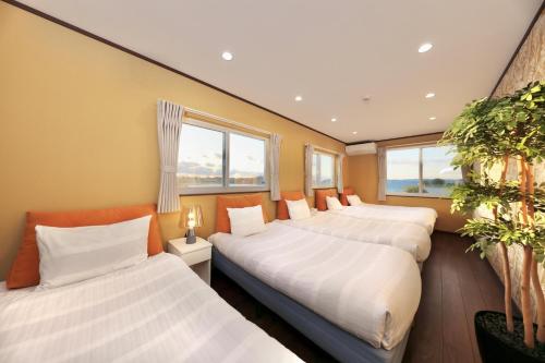 three beds in a room with windows at Crystal Besso Uminomachi in Shirahama