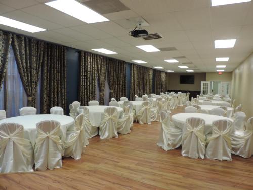 a room full of tables and chairs with white bows at Airport Inn in Nederland