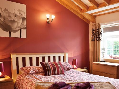 una camera da letto con pareti rosse, un letto e una finestra di Magpie Cottage a Gristhorpe