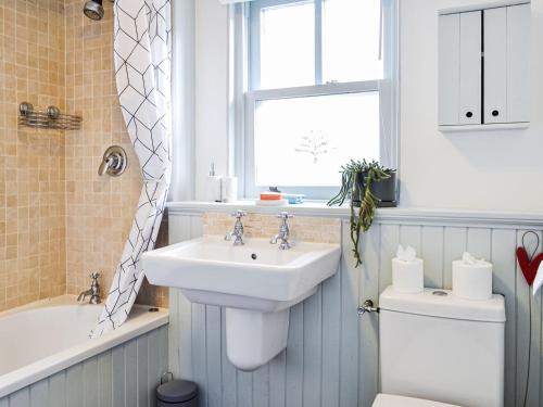 baño con lavabo y aseo y ventana en Oakwood Cottage, en Glencoe