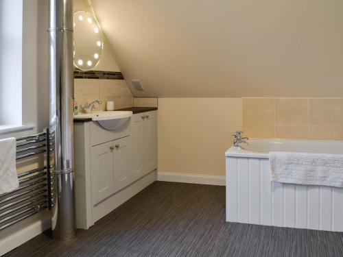 a bathroom with a sink and a bath tub at Liftingstane Farmhouse in Closeburn