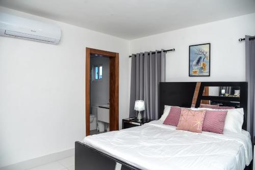 a bedroom with a large white bed with pink pillows at Torre Real VI in Santiago de los Caballeros