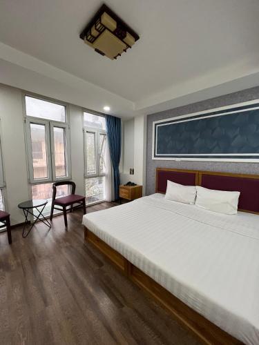 a bedroom with a large white bed and two windows at Holiday Suites Hotel & Spa in Hanoi