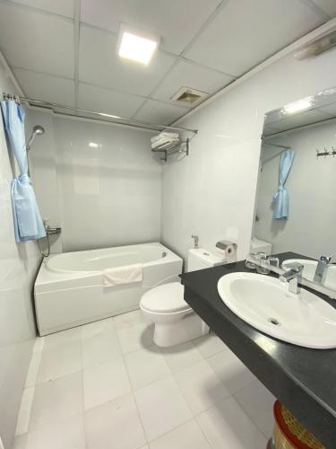 Holiday Suites Hotel & Spa في هانوي: حمام مع حوض ومرحاض ومرآة