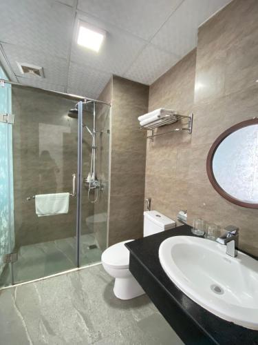 a bathroom with a sink and a toilet and a glass shower at Holiday Suites Hotel & Spa in Hanoi