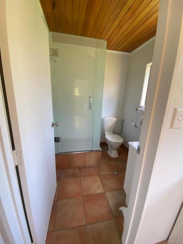 a bathroom with a toilet and a glass shower at Unit 1 Kaiteri Apartments and Holiday Homes in Kaiteriteri