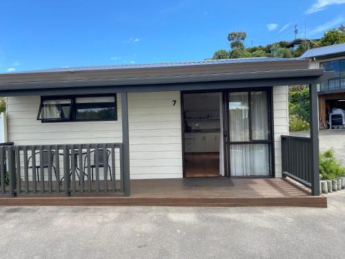 a small house with chairs on a deck at Unit 1 Kaiteri Apartments and Holiday Homes in Kaiteriteri