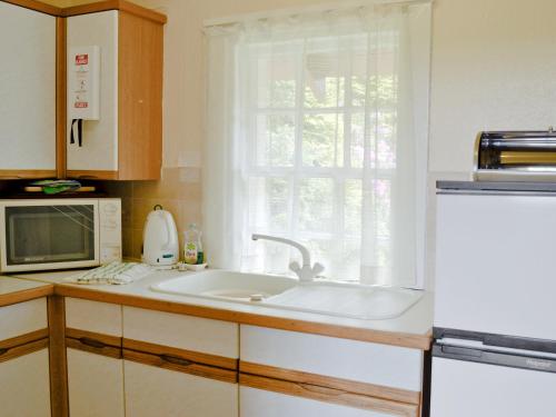 a kitchen with a sink and a microwave and a window at Ardmore in Largs
