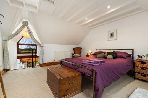 a bedroom with a purple bed and a window at Trellys Hyfryd - cottage in Fishguard