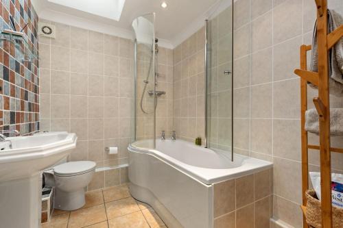 a bathroom with a tub and a toilet and a sink at Trellys Hyfryd - cottage in Fishguard