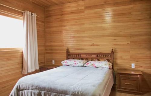 1 dormitorio con 1 cama y pared de madera en Casa do Guiga en São Joaquim