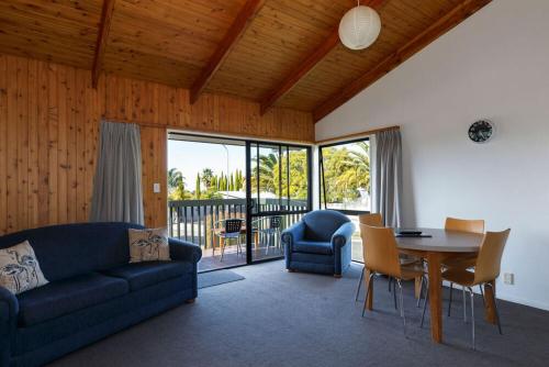 a living room with a couch and a table and chairs at Unit 2 Kaiteri Apartments and Holiday Homes in Kaiteriteri