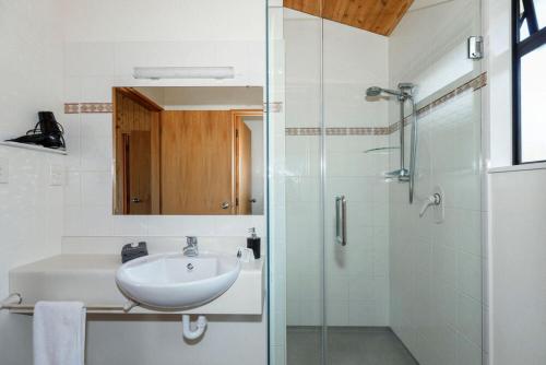 a white bathroom with a sink and a shower at Unit 2 Kaiteri Apartments and Holiday Homes in Kaiteriteri