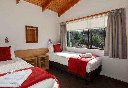 a hotel room with two beds and a window at Unit 2 Kaiteri Apartments and Holiday Homes in Kaiteriteri