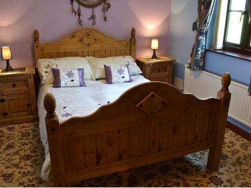 a bedroom with a wooden bed with two pillows on it at Rallt Fawr in Gwalchmai