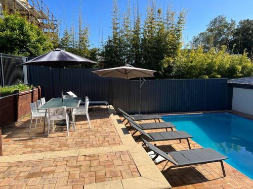 a patio with a table and chairs and an umbrella at Bundeena Base Art House in Bundeena