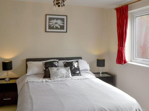 a bedroom with a white bed with pillows and a window at Tracara Cottage in Horning