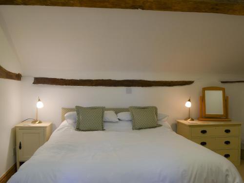 a bedroom with a large white bed with two lamps at Oak Barn Cottage in Trefonen
