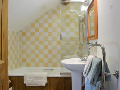 a bathroom with a sink and a bath tub and a sink at Oak Barn Cottage in Trefonen
