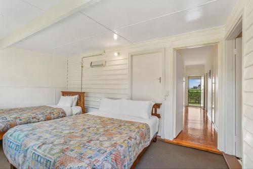 a bedroom with two beds and a hallway with a window at Aisling Cottage in Port Fairy