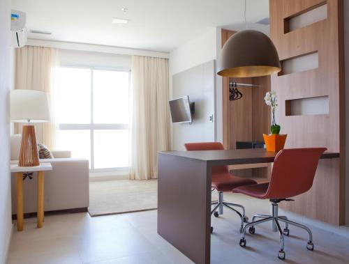 a living room with a desk and red chairs at Intercity Brasilia Led Aguas Claras in Brasilia