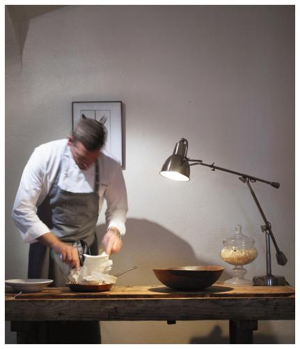a woman in a kitchen preparing food on a table at Relais & Châteaux Taubenkobel in Schützen am Gebirge