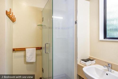 a bathroom with a glass shower and a sink at Unit 7 Kaiteri Apartments and Holiday Homes in Kaiteriteri