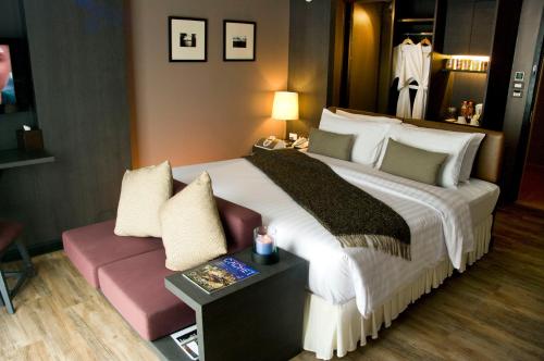 AYA Boutique Hotel Pattaya - SHA Plus في باتايا سنترال: غرفة فندقية بسرير كبير واريكة
