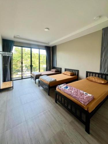 a room with three beds and a large window at The Villa Sai yok noi in Khlong Luang